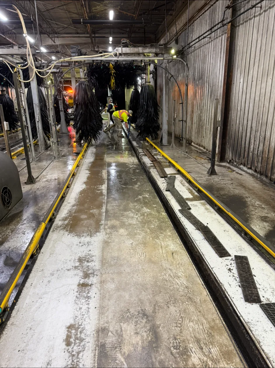 Worker cleaning the trench area of a car-wash lane