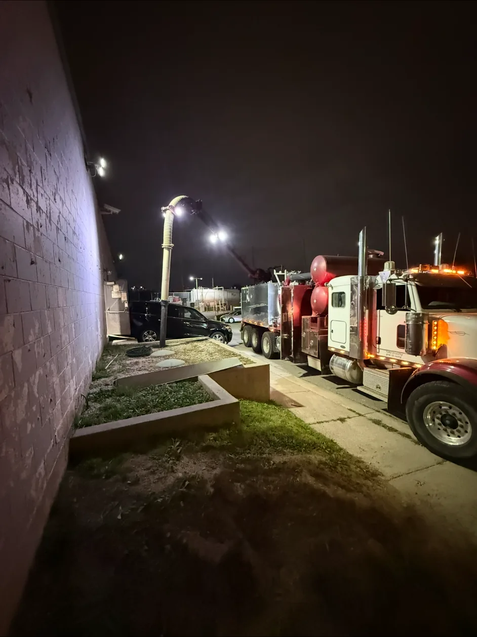 Vacuum truck working beside a commercial building at night