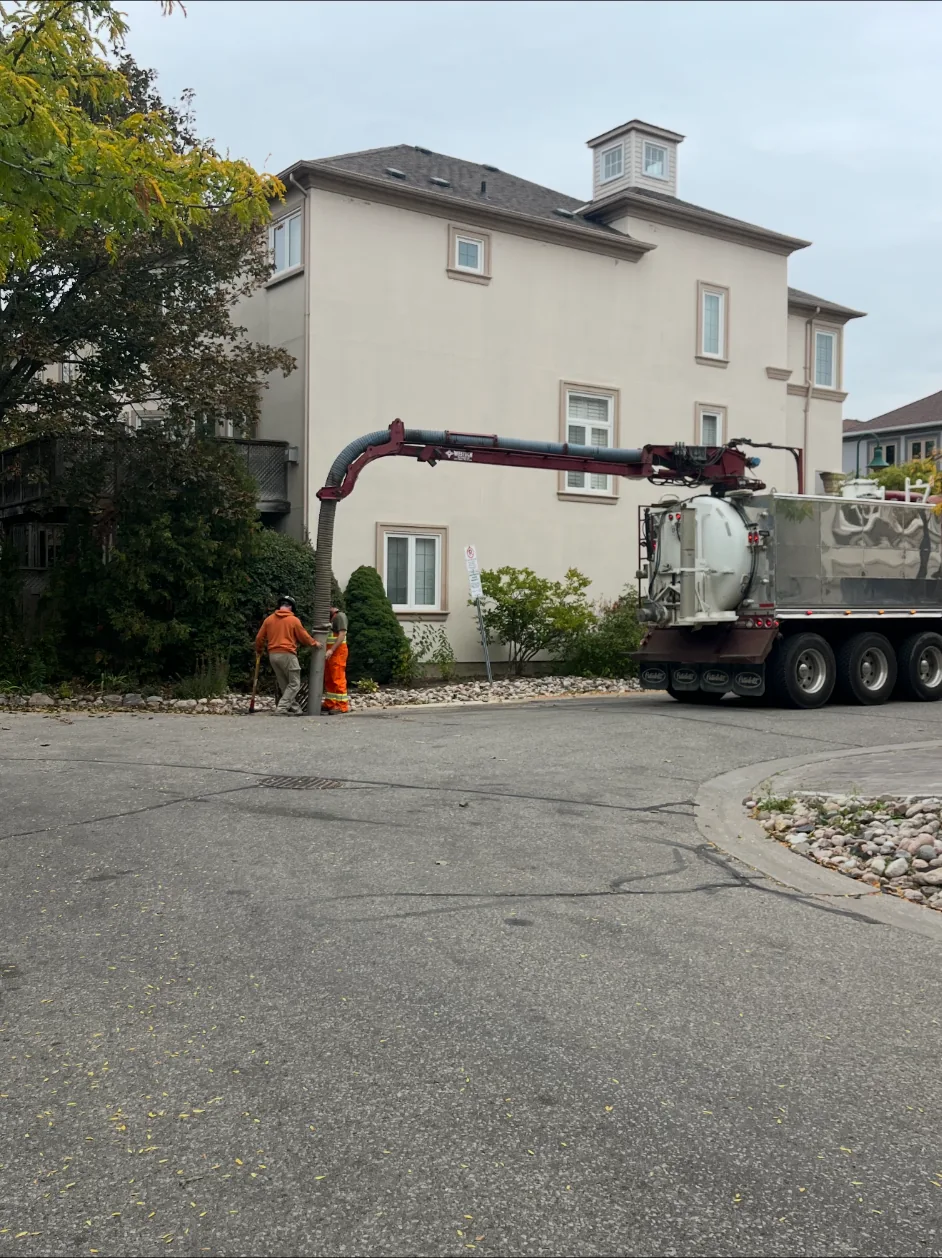 Vacuum truck and crew working beside a residential street